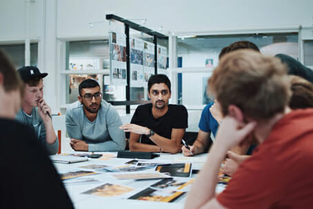 group of people discussing designs with photos laid out on table