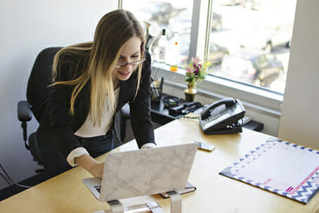 Woman standing and leaning into laptop on stand