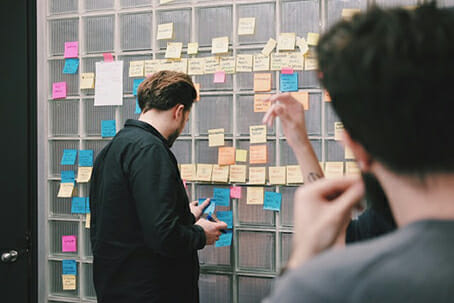 man in black jacket putting sticky notes onto a wall